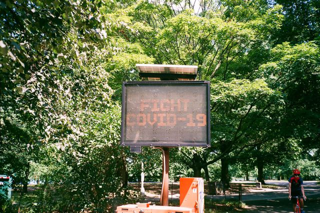 A photo of a digital street sign that reads "FIGHT COVID-19"